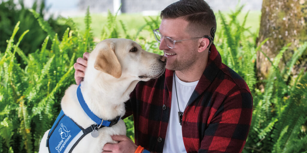 man and a Labrador sitting on a bench, with the man embracing the dog