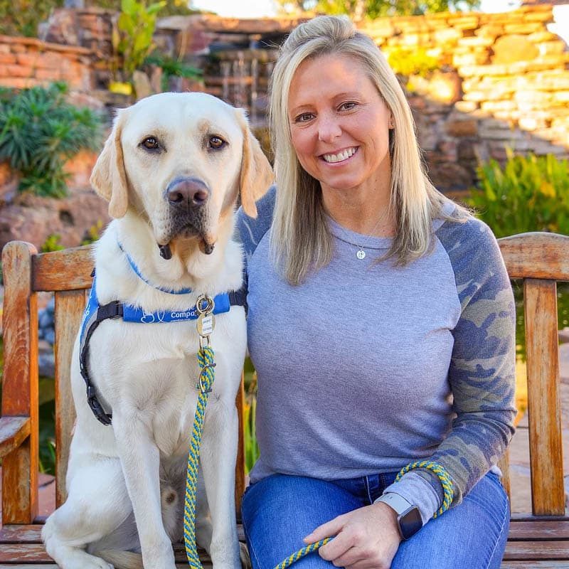 brisket_grad a smiling woman with a yellow labrador retriever in a blue service vest
