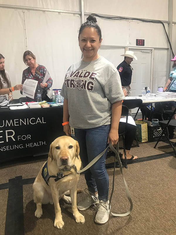 Woman in Uvalde Texas holds the leash of a yellow lab in a blue service dog vest