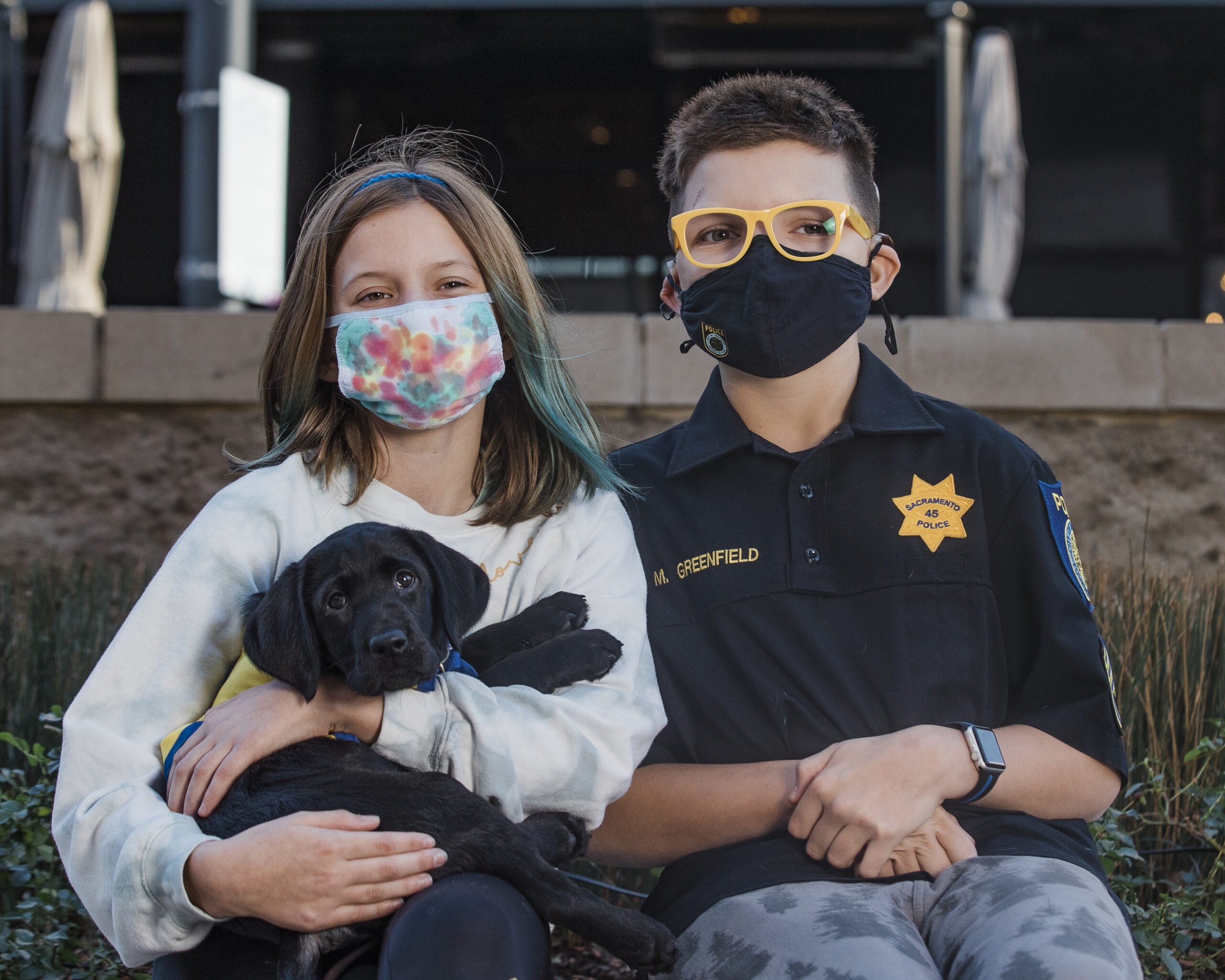 two people sitting and holding a Canine Companions puppy