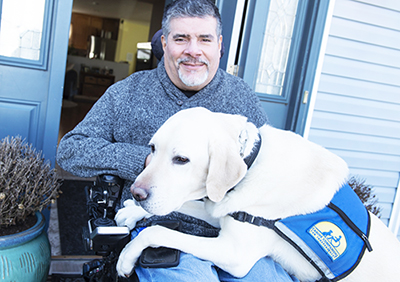 man sitting in chair with Canine Companions service dog