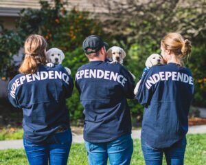 3 people holding puppies and wearing Independence jerseys