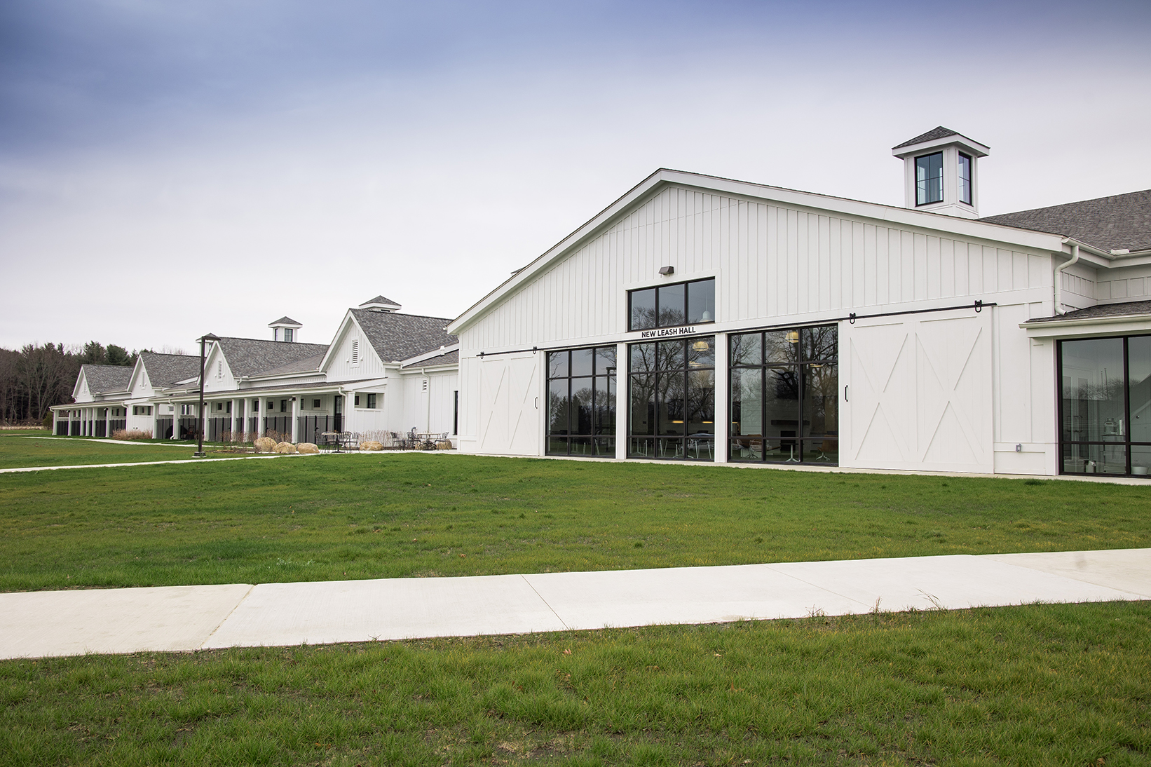 Large white building with pictures windows surrounded by grass field