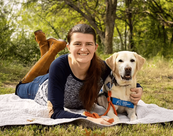 Young woman lying down on the grass with her hearing dog